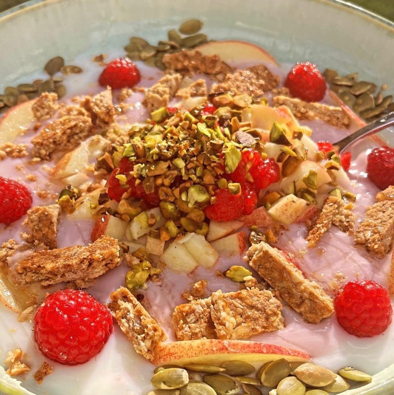 Pistachio yogurt bowl with raspberries, pear and granola
